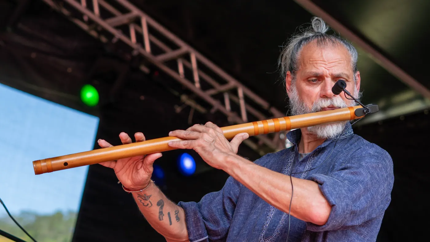 Músico tocando flauta transversal no palco do festival