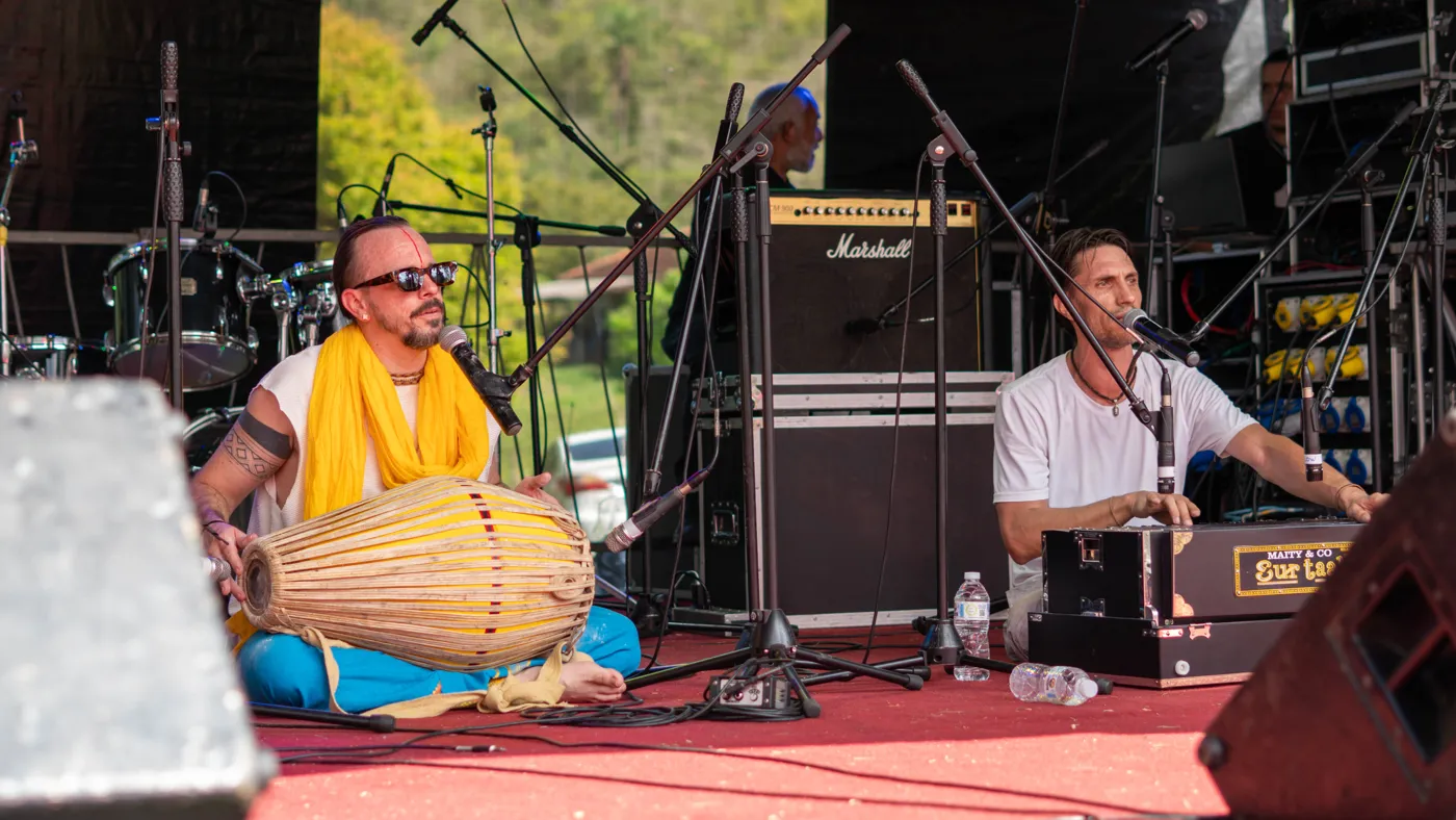 Músicos sentados com instrumentos indianos em apresentação no palco