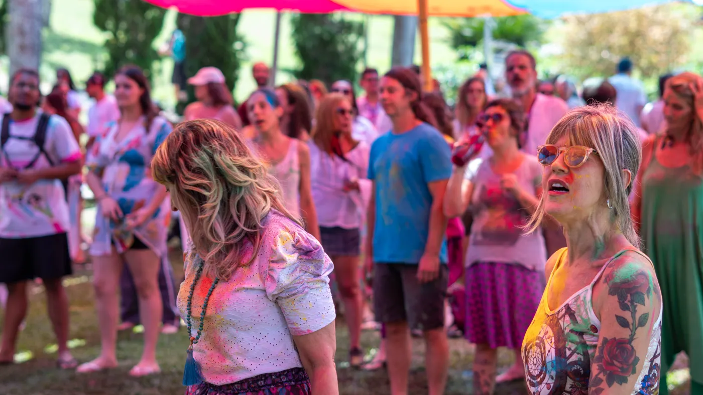 Multidão dançando ao som do palco com tecidos coloridos ao fundo