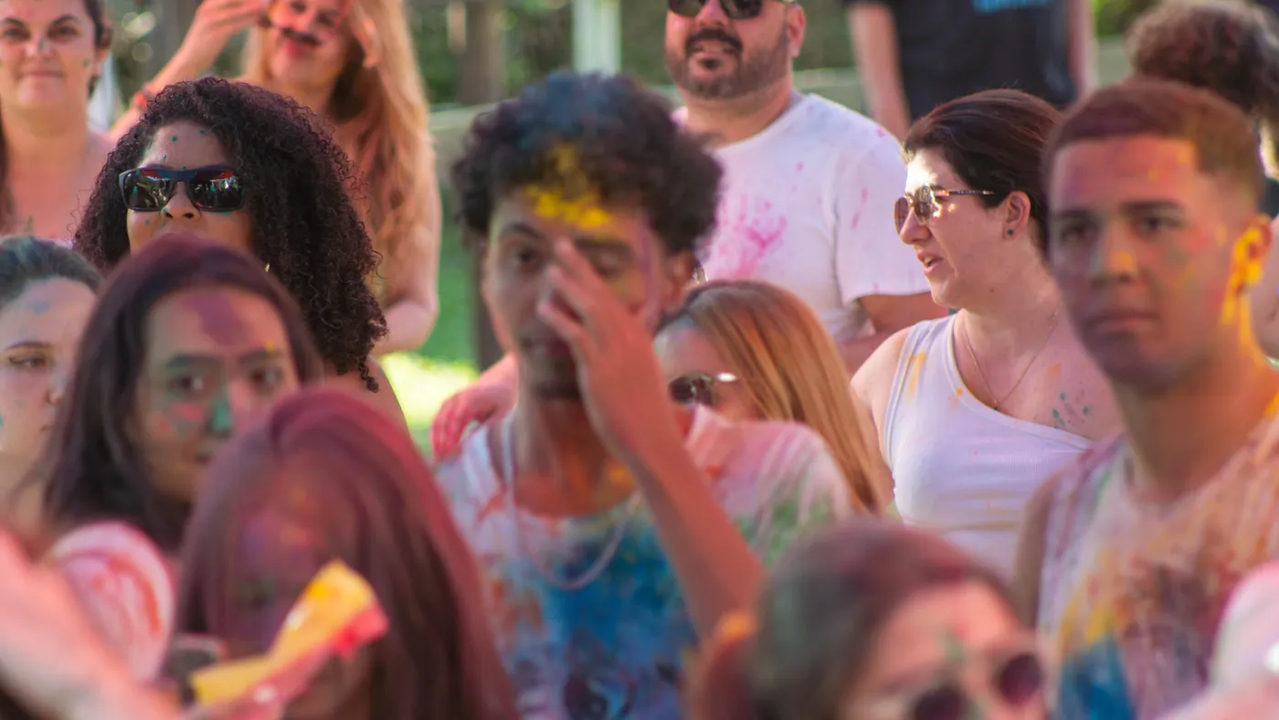 Participantes com rostos cobertos de pó colorido sorrindo para a câmera