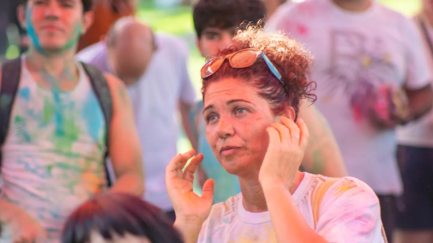 Jovem com o rosto pintado de pó colorido no meio da multidão