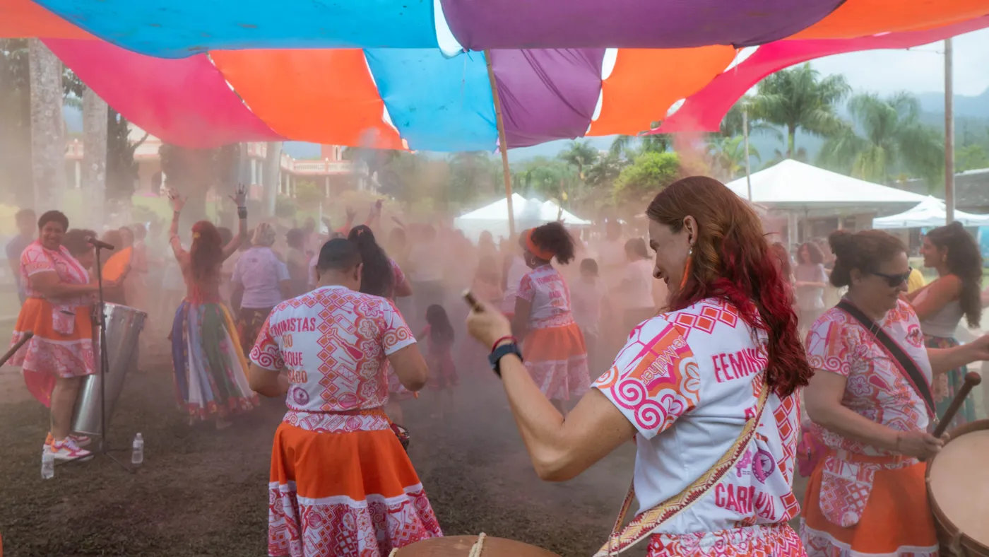 Roda de dança com pó colorido no ar sob tecidos coloridos