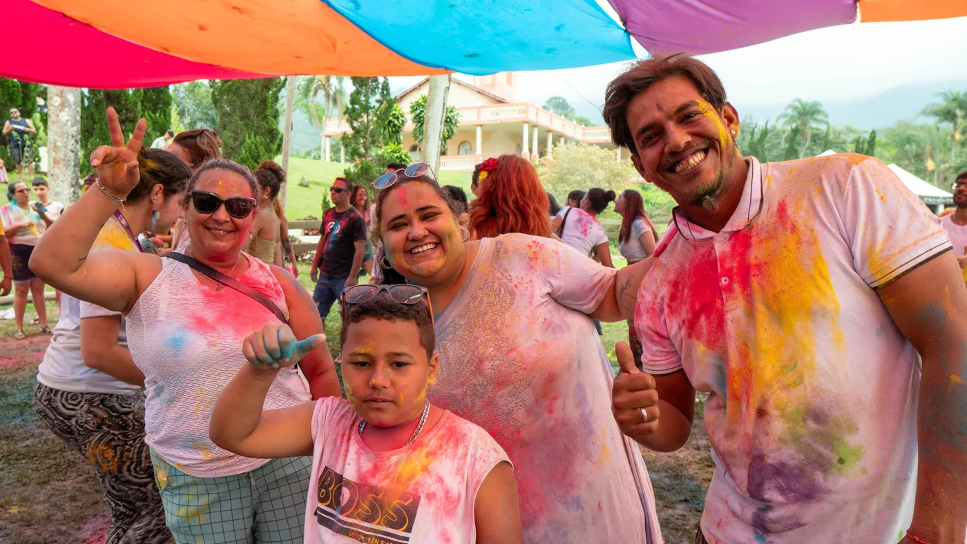 Pai e filhos cobertos de pó colorido sorrindo juntos