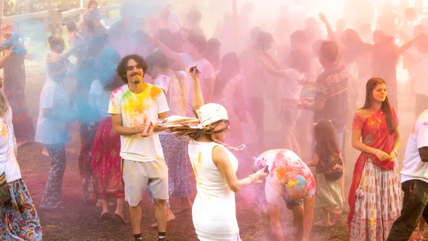Crianças e adultos brincando com pó colorido em meio a nuvem de cores